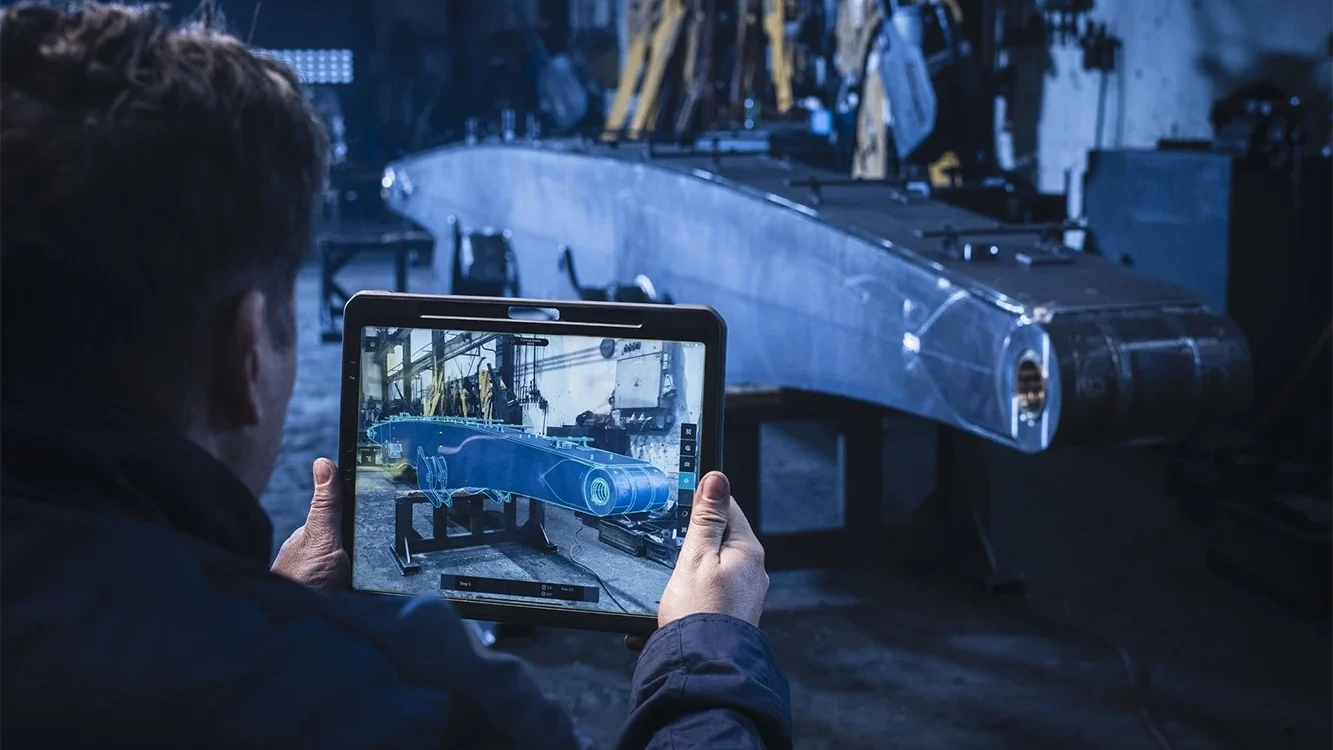 Mitarbeiter prüft ein Bauteil mit Tablet und AR-Overlay in Twyn 2.6 für eine effizientere visuelle Qualitätsinspektion.